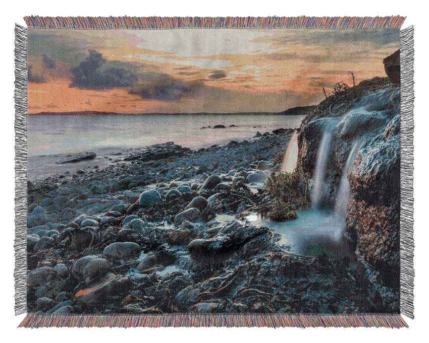 Water flows down the rocks into the sea Woven Blanket